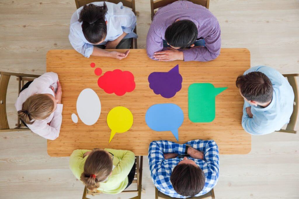 Photograph of people sitting around a table with different ideas