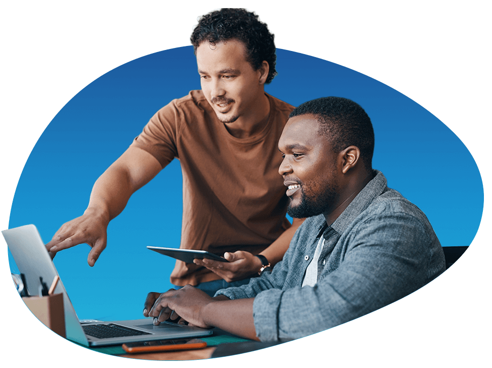 Two individuals coordinating on a laptop and tablet to reflect shared responsibility in co‑managed IT support.