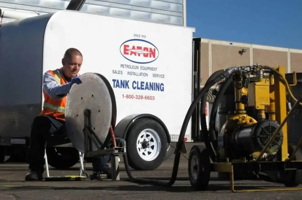 Technician servicing industrial tank cleaning equipment beside an Eaton Metal Products trailer at a manufacturing facility in Denver, Colorado.